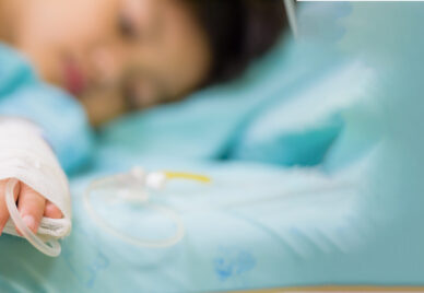 A child on a hospital bed, recieving saline intravenous