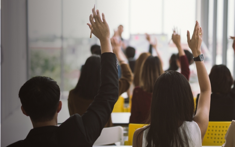 diverse people raising their hands in a classroom