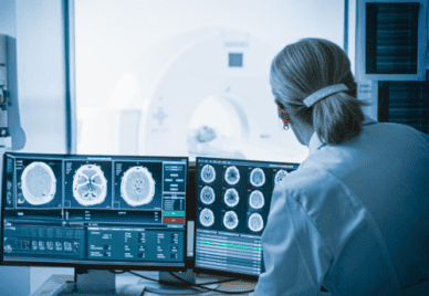 doctor looking at computer screens with brain scans on them