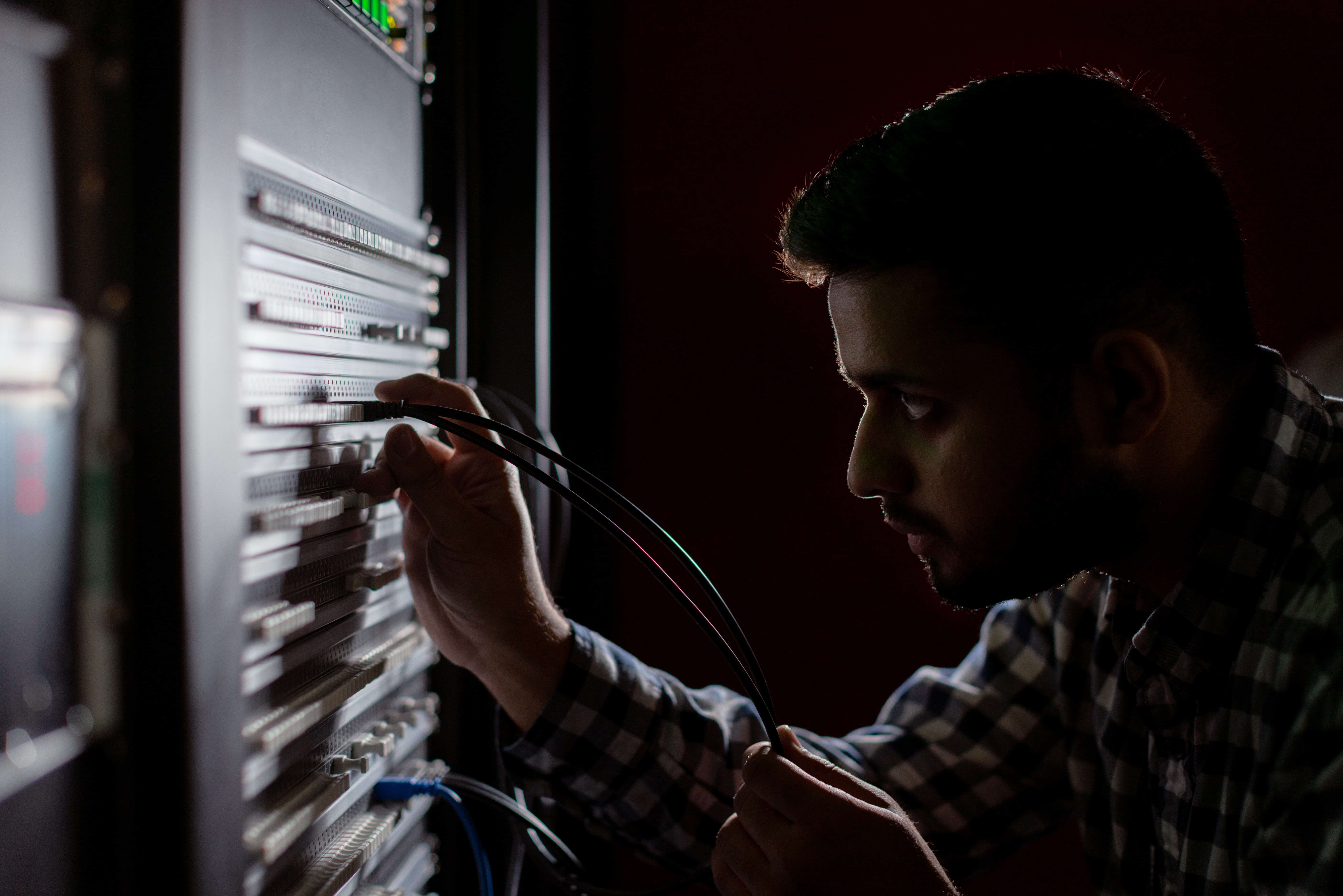 An engineer plugging a cable in a dark room