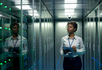 A person with a tablet in a corridor at a data center, checking hardware on server racks