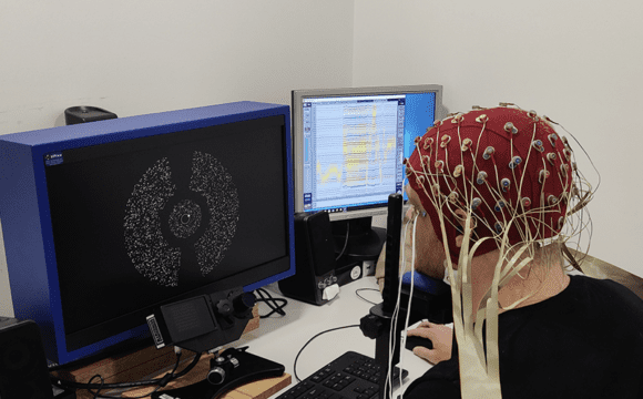 A participant of a experiment performing a task at a computer with EEG electrodes attached to their head