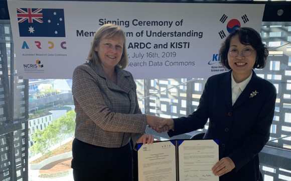 Rosie Hicks and Dr Hee-yoon Choi shaking hands and holding up a signed document in front of a banner that reads "Signing Ceremony of Memorandum of Understanding Between ARDC and KISTI, July 16th, 2019"