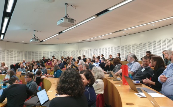 A lecture room full of people talking to one another