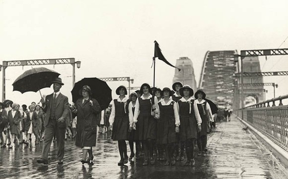 A black-and-white photo of schoolchildren in a parade on the Sydney Harbour Bridge on a rainy day