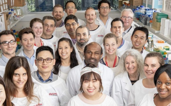 A group of people in a lab wearing white shirts with Griffith University's logo