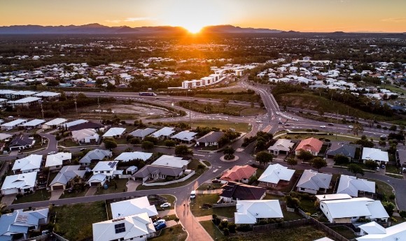 Aerial view of Townsville suburb, with houses, roads and sunset in the distance