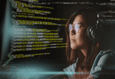 A person wearing glasses and headphones look at computer code