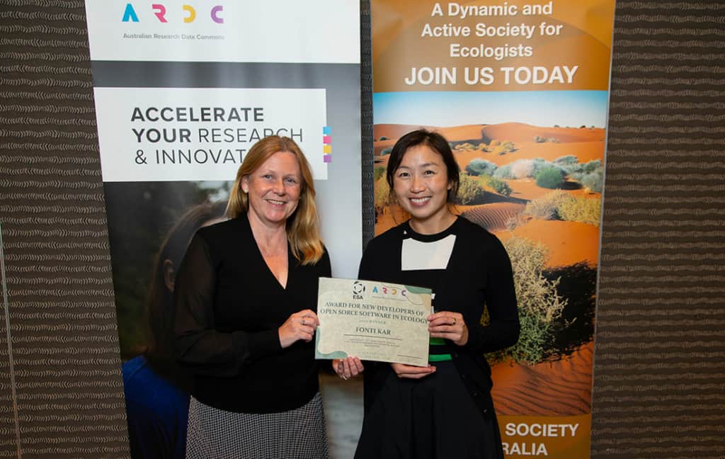 Rosie Hicks presents the Ecological Society of Australia Award for new developers of open source software in ecology to Dr Fonti Kar from AusTraits. ARDC and ESA banners in the background.