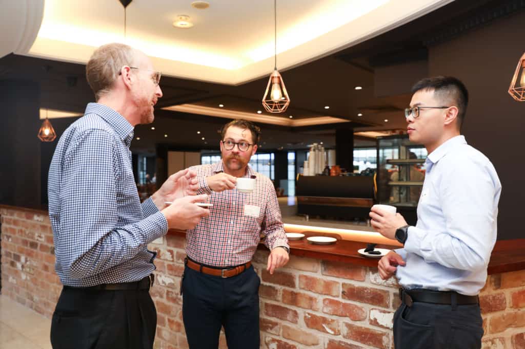 Three attendees having a conversation over light refreshments