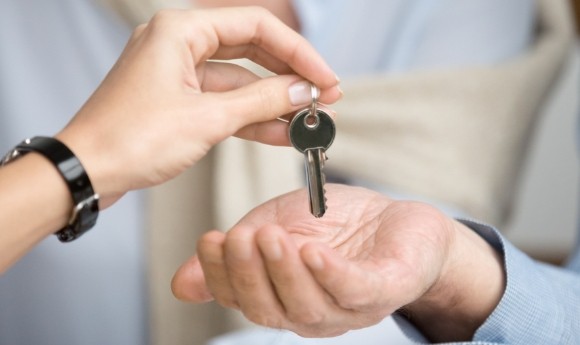 A person handing a key to another