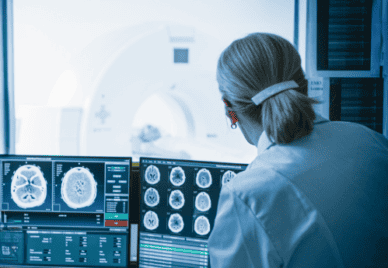 doctor looking at computer screens with brain scans on them