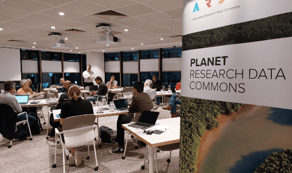 ARDC Planet Research Data Commons banner with a room of people in a workshop behind.