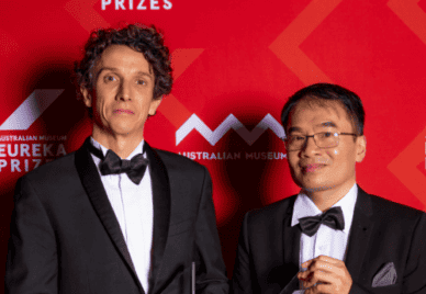 Dr Minh Bui and Professor Robert Lanfear from The Australian National University stand with their Eureka Prizes in black tie infront of a red background