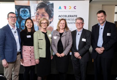 Six people standing in front of an A R D C banner featuring a pateitn looking at a medical scan