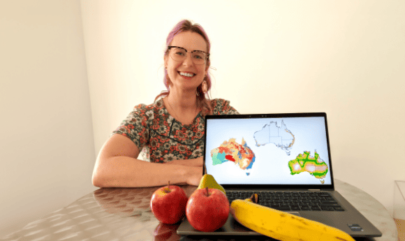 Dr Nina Welti, CSIRO's trusted supply chains expert, with a laptop with maps of Australia and some fruit on the key board.