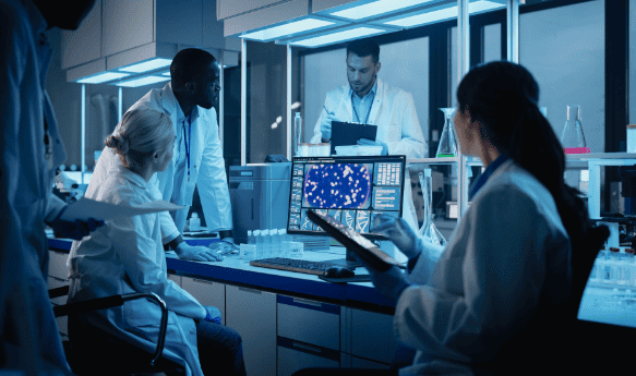 Four medical researchers gathering around a computer in a lab