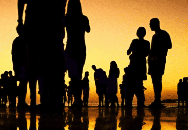 Silhouettes of people standing at sunset on the sea shore