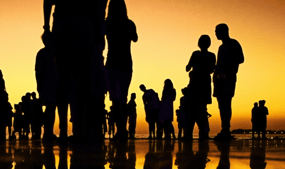 Silhouettes of people standing at sunset on the sea shore