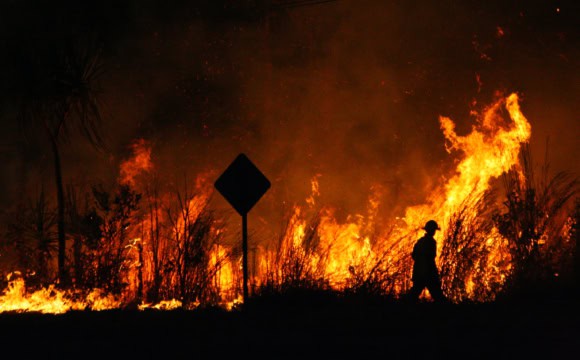 A firefighter silhouetted against a bushfire
